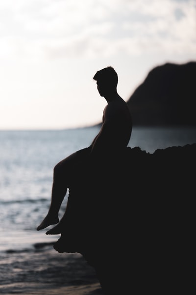 The man sat on a cliff silhouette photography

